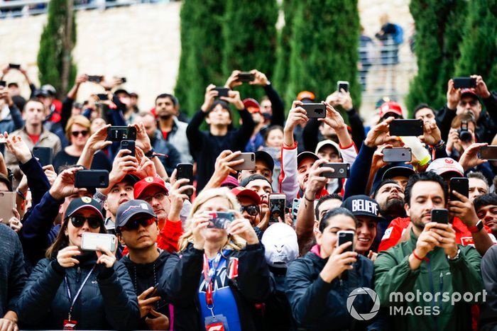 Los aficionados toman fotos de los conductores con sus teléfonos móviles.