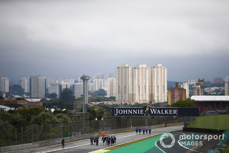 Vista de Sao Paulo detrás del circuito, en primer plano Pierre Gasly, Toro Rosso y los miembros del equipo caminan por el circuito, junto con Sergio Pérez, Force India