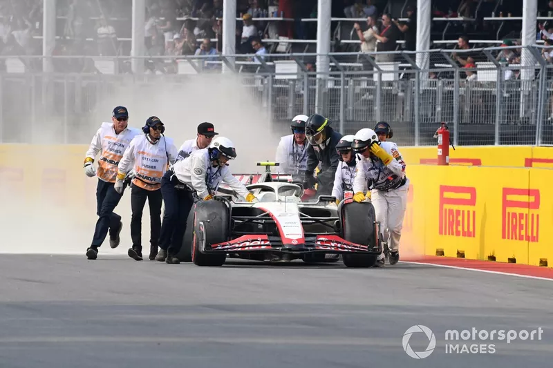 I commissari tentano di spegnere un incendio sulla vettura di Nico Hulkenberg, Haas VF-23