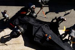 McLaren mechanics push the covered Stoffel Vandoorne McLaren MCL32 into its garage after it encountered a technical problem on track