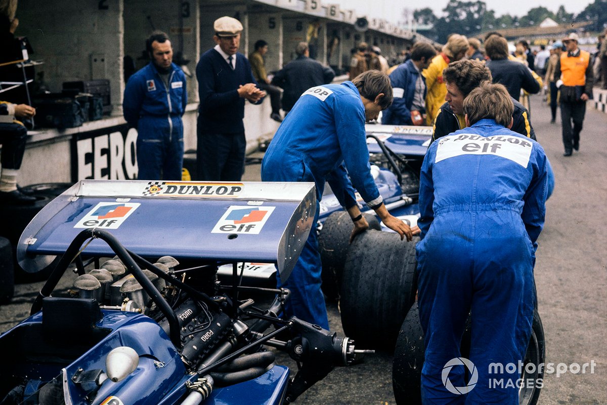 Tyrrell mechanics change the tyres on their cars in the pit lane as overseen by Ken Tyrrell