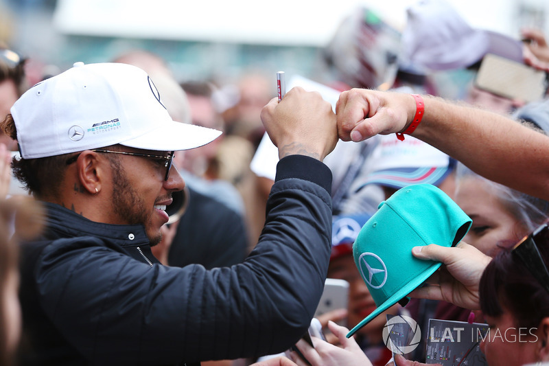 Lewis Hamilton, Mercedes AMG F1, bumps fists with a fan, in between signing autographs