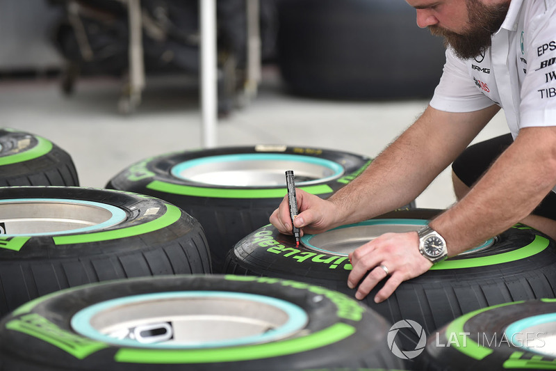 Un mécanicien Mercedes AMG F1 marque des pneus Pirelli