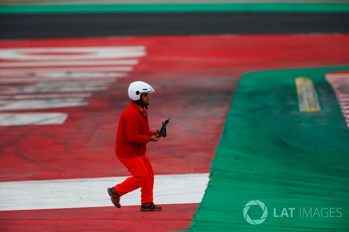 Un mariscal recoge un pedazo de escombros de la pista