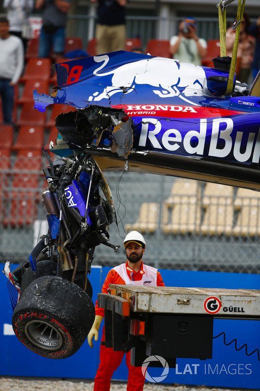 Marshals remove the damaged car of Brendon Hartley, Toro Rosso STR13, from the circuit as the gearbox hangs off the back