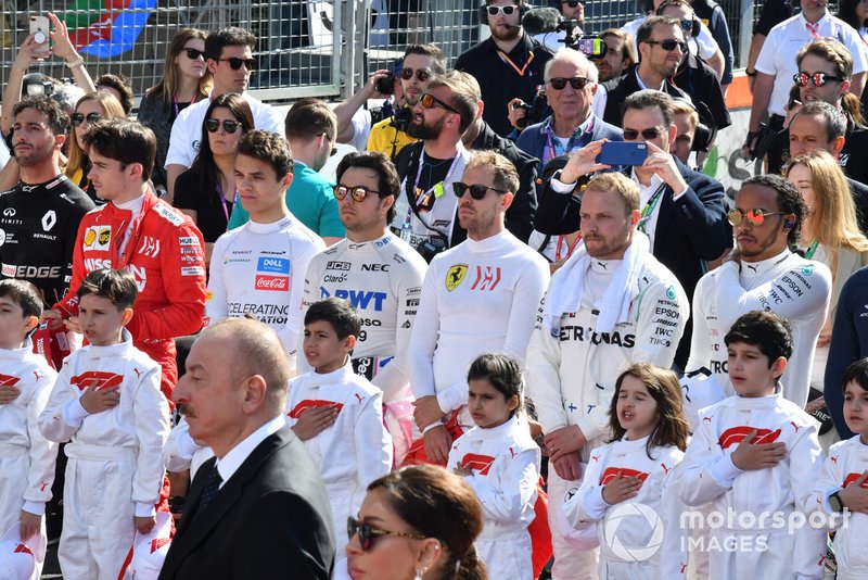 The drivers and Grid Kids stand for the national anthem prior to the start