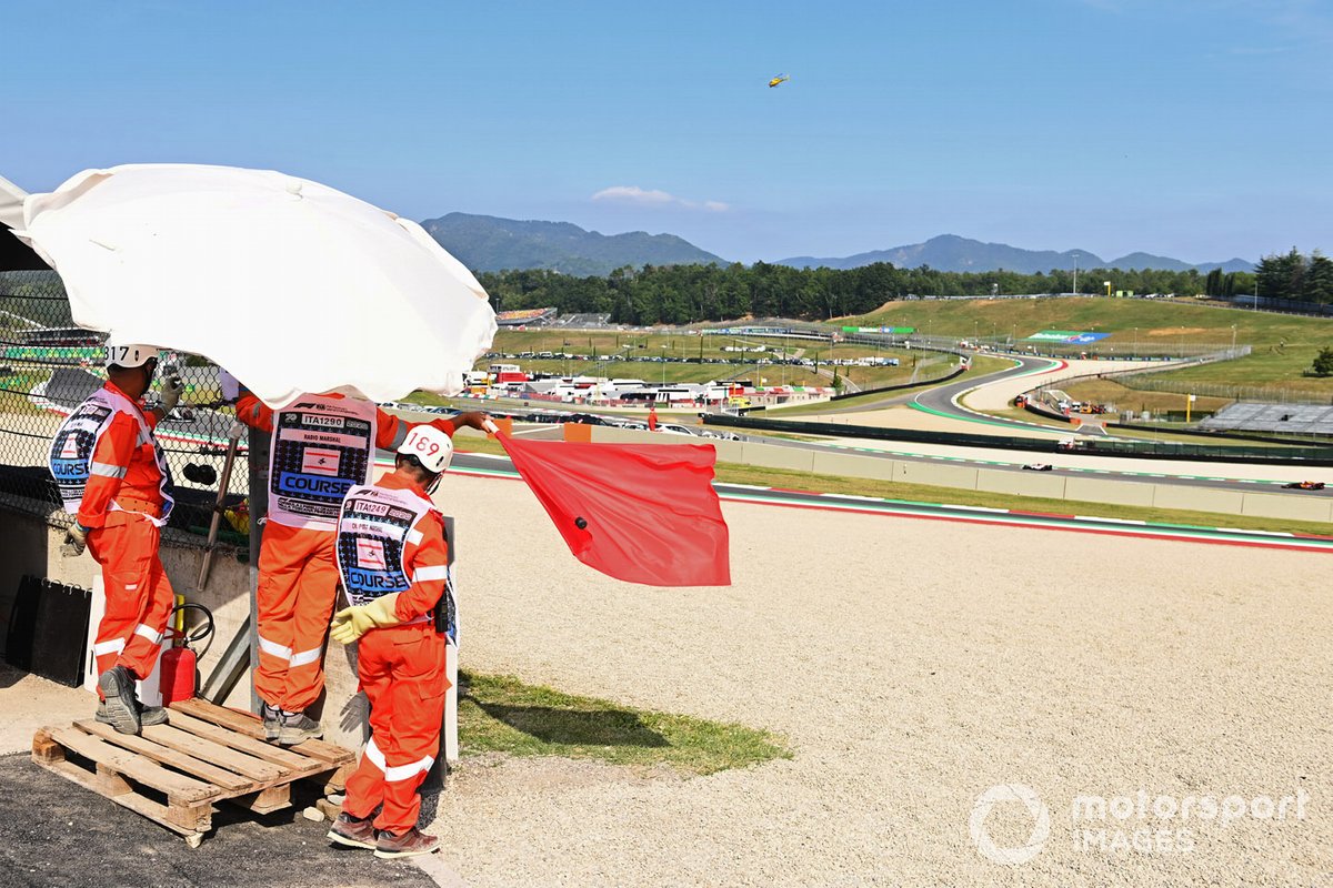 Los oficiales de pista agitan la bandera roja durante la FP2