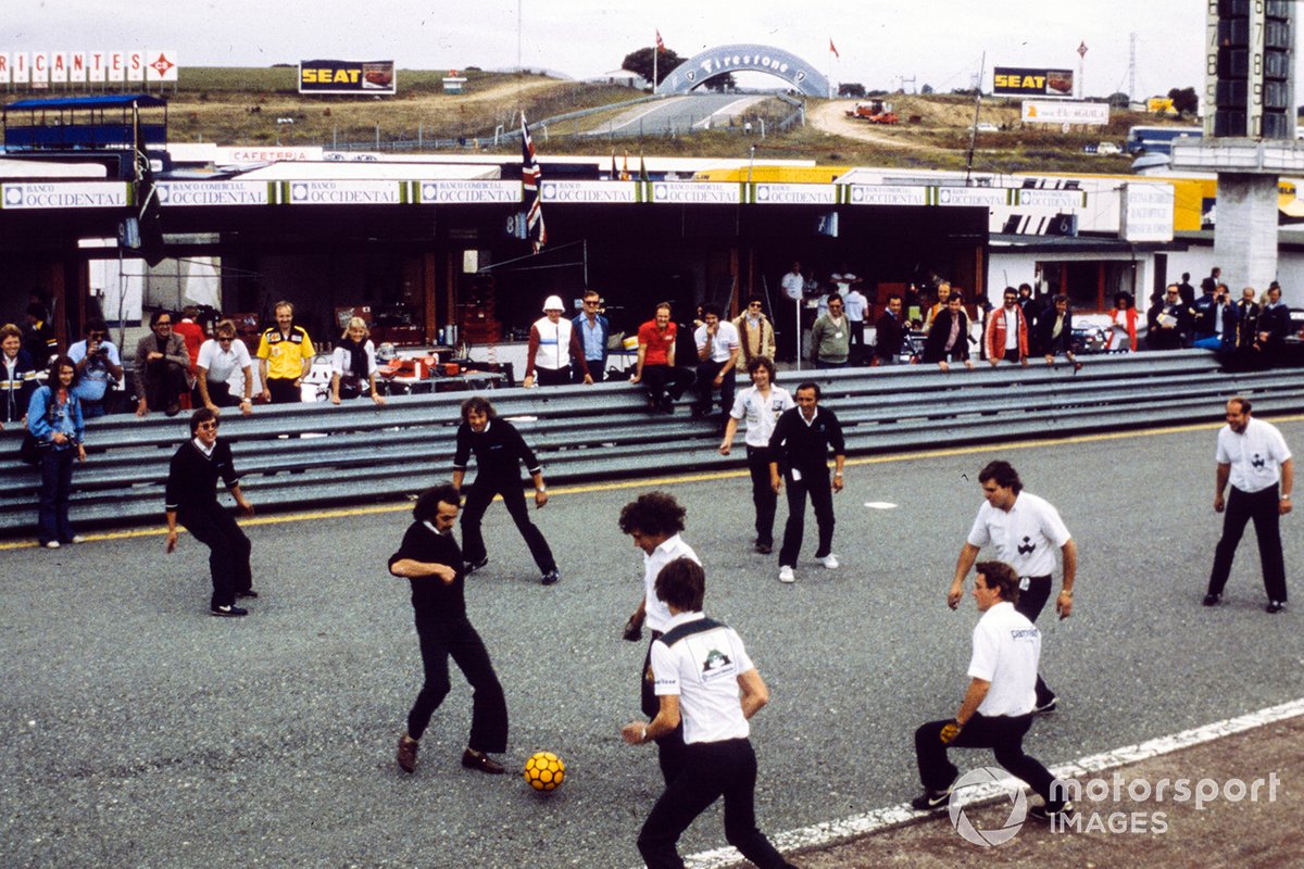 Los mecánicos de Brabham y Williams juegan al fútbol en la parrilla. Nelson Piquet se sienta en el pit wall a mirar