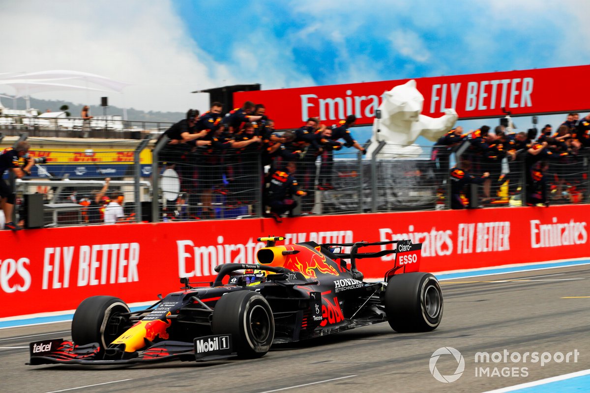 Sergio Perez, Red Bull Racing, posisi ketiga, melewati garis finis dan disambut sorak-sorai timnya di dinding pit