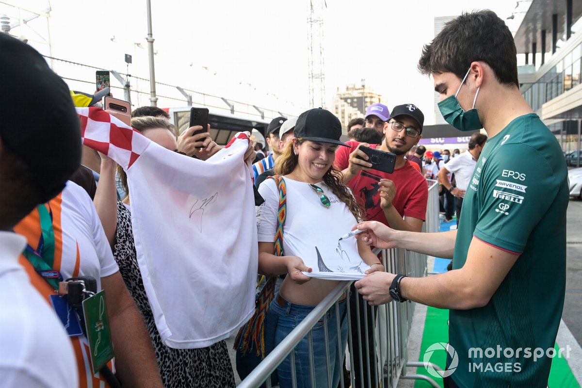 Lance Stroll, Aston Martin, firma una camiseta para un aficionado