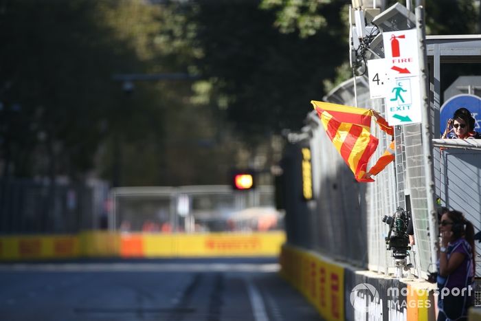 Los comisarios despliegan la bandera roja y amarilla de condiciones de la pista