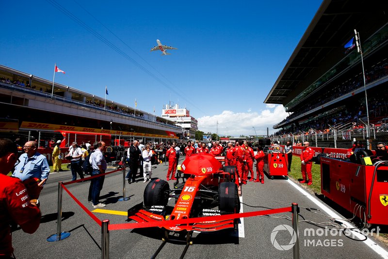 The car of Charles Leclerc, Ferrari SF90, on the grid as an Emirates Airbus A380 flies over