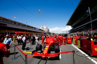 The car of Charles Leclerc, Ferrari SF90, on the grid as an Emirates Airbus A380 flies over
