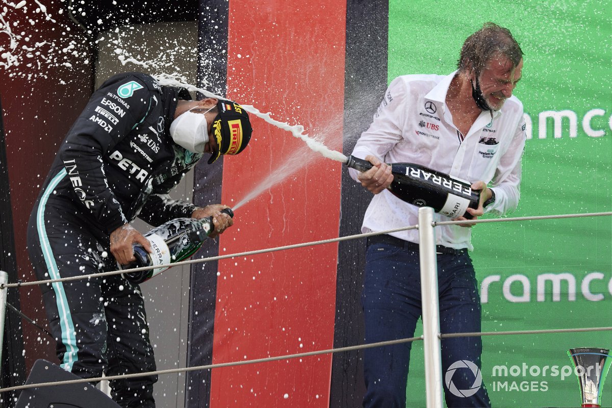 Lewis Hamilton, Mercedes, primera posición, y el encargado de Mercedes de recoger el trofeo se bañan con champán en el podio.