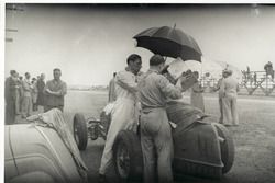 Während einer Trainingspause zum GP von Südafrika 1937 in East London wird der Alfa Romeo 8C 3800 von Hans Rüesch (links) bei Regen getankt. Beim Alfa Romeo handelt es sich um ein ehemaliges Fahrzeug der Scuderia Ferrari