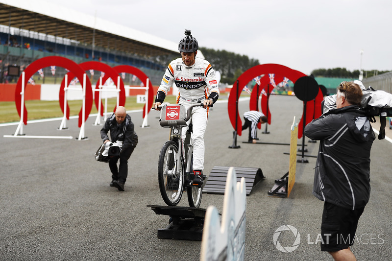 Jenson Button, McLaren, rides a bicycle over an assault course