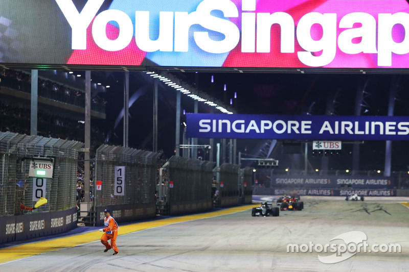 Un marshal corre lungo il circuito mentre Nico Rosberg, Mercedes AMG F1 W07 Hybrid è al comando alla