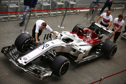 Sauber team members wheel the Marcus Ericsson Sauber C37 in the pit lane