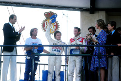 Exhausted race winner Gilles Villeneuve, Ferrari, centre, takes the applause as Jaques Laffite, Ligier, left, and John Watson, McLaren, right, look on