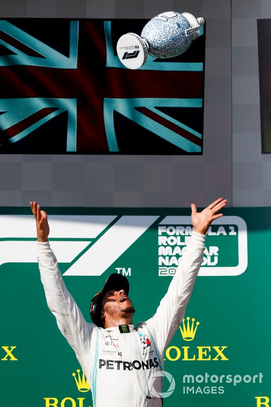 Il primo classificato Lewis Hamilton, Mercedes AMG F1, lancia il suo trofeo in aria per festeggiare sul podio