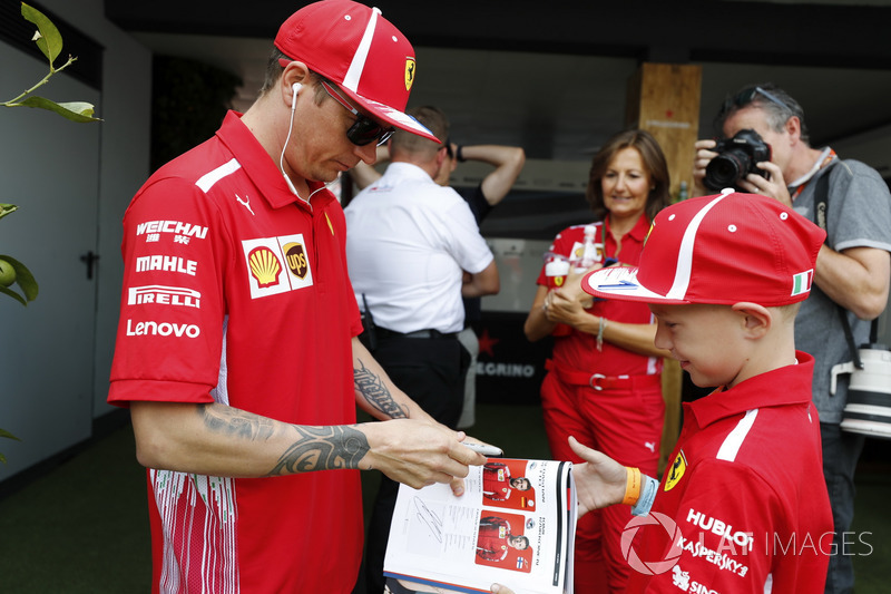 Kimi Raikkonen, Ferrari, signs an autograph for a young fan