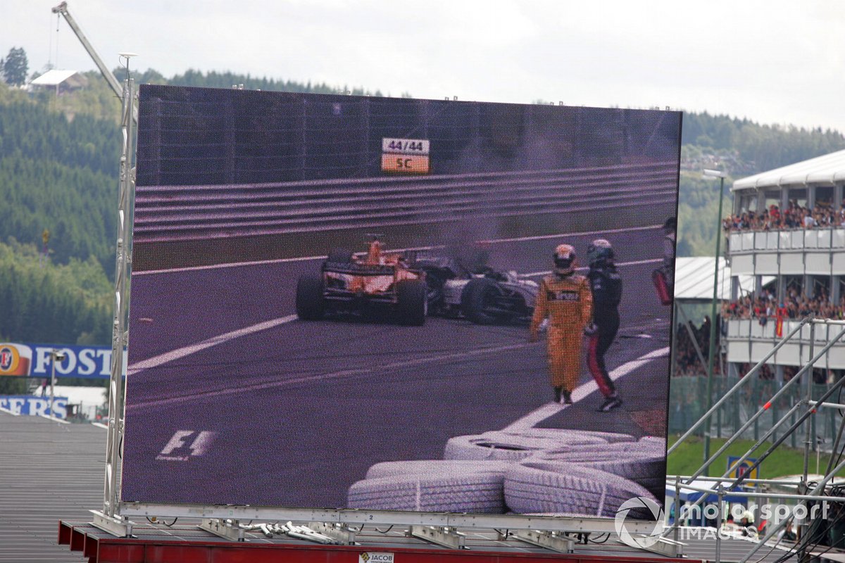 The big screen shows the first lap crash between Giorgio Pantano, Jordan Ford EJ14 and Gianmaria Bruni, Minardi Cosworth PS04B