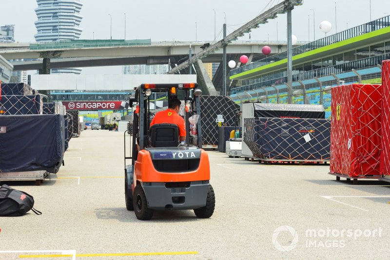 A forklift truck negotiates freight belonging to Ferrari and Red Bull on the pit straight