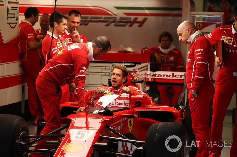 Sebastian Vettel, Ferrari, lowers himself into the cockpit of his car fitted with a new protective shield