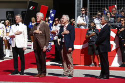 Michael Buffer and former US President Bill Clinton and Chase Carey, Chairman, Formula One, stand for the national anthem