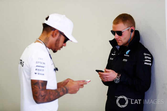 Valtteri Bottas y Lewis Hamilton utilizan sus móviles antes de la carrera