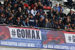 A large group of Max Verstappen, Red Bull Racing, supporters sit above a banner in the grandstand