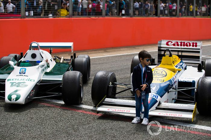 A young fan stands in front of a Williams FW08 and FW11