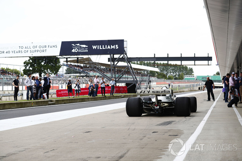 A Williams FW07 arrives in the pit lane