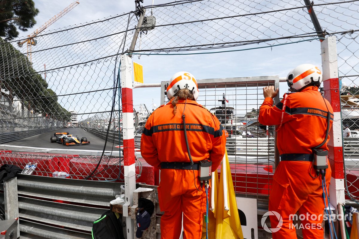 Oficiales de pista ven a Daniel Ricciardo, McLaren MCL35M, pasar
