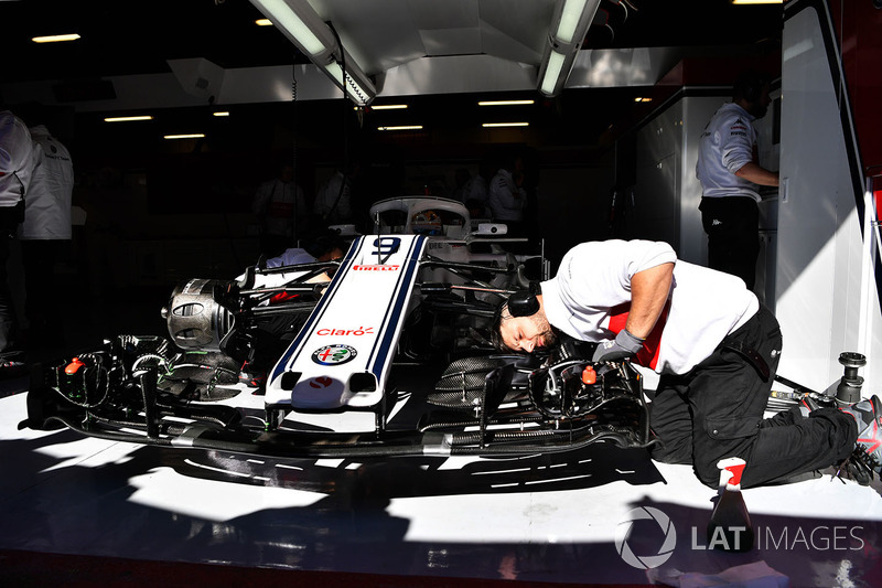 Механики Alfa Romeo Sauber работают над автомобилем C37 в гараже