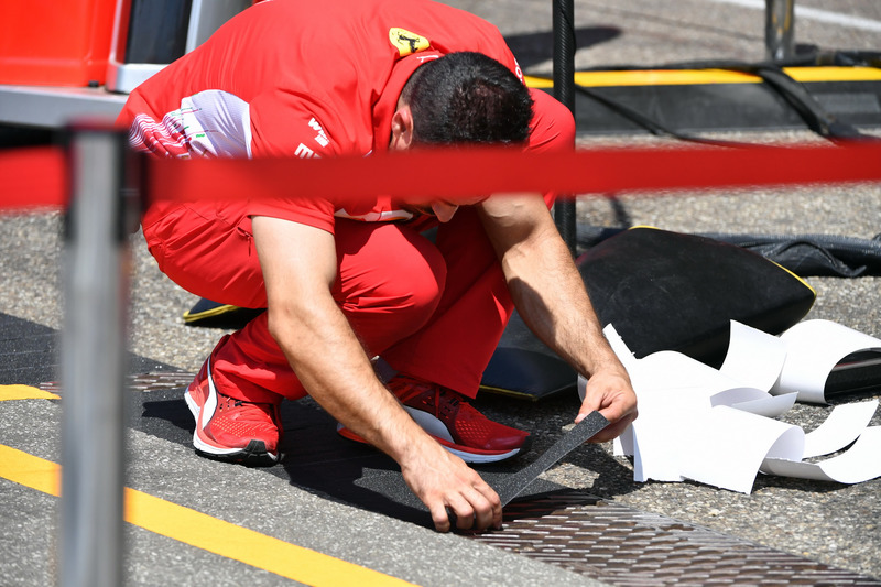 Un mécanicien Ferrari place les marques au sol dans les stands