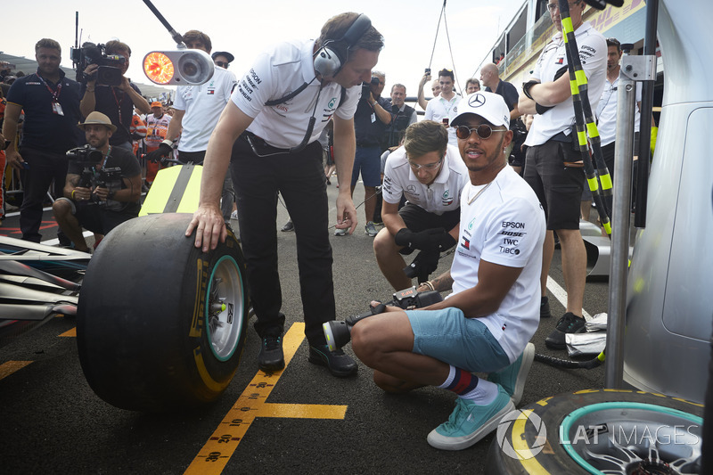 Lewis Hamilton, Mercedes AMG F1, tries his hand with a wheelgun on the car of his team mate