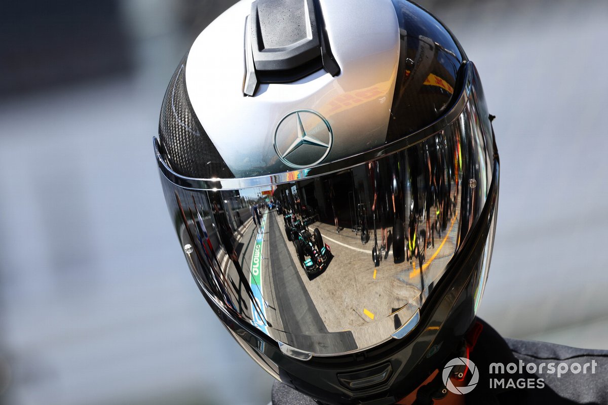 El coche de Lewis Hamilton, Mercedes W12, reflejado en el casco de un mecánico