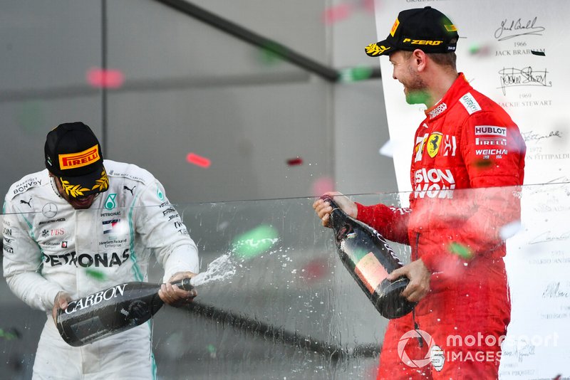 Lewis Hamilton, Mercedes AMG F1, 2nd position, and Sebastian Vettel, Ferrari, 3rd position, spray Champagne at each other on the podium
