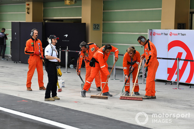 Marshals clean the Haas F1 pit box