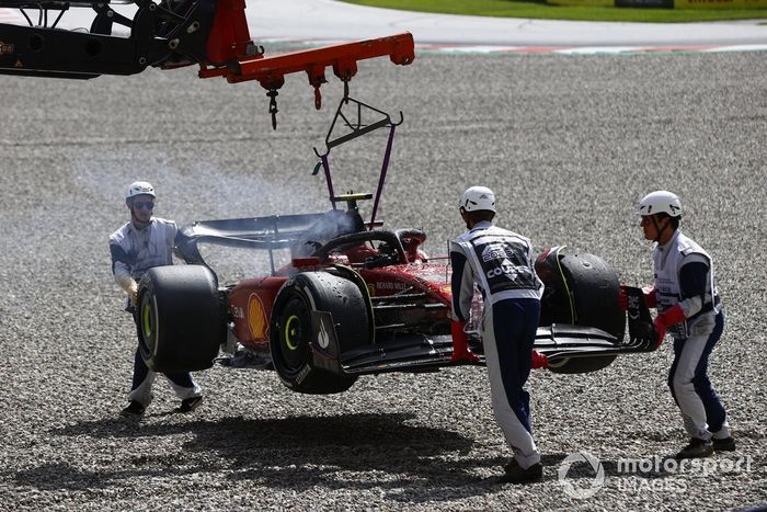 Los oficiales de pista retiran del circuito el coche incendiado de Carlos Sainz, el Ferrari F1-75