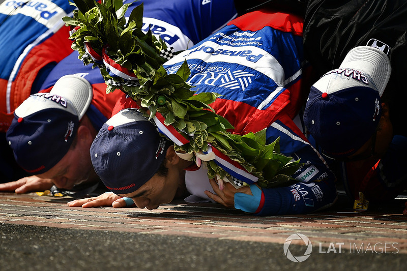 Pemenang balapan Takuma Sato dan kru tim Andretti Autosport Honda mencium garis finis 'Yard of Bricks'