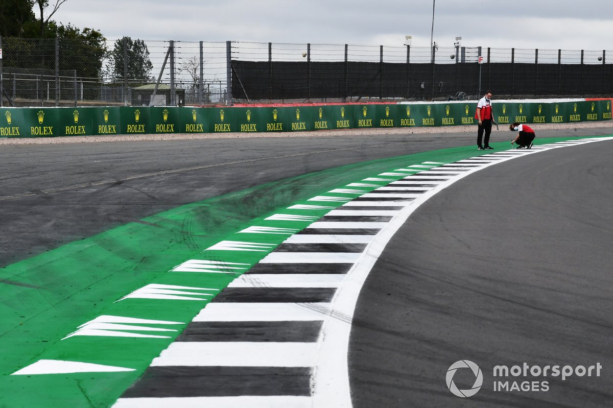 Los miembros del equipo Alfa Romeo inspeccionan un bordillo