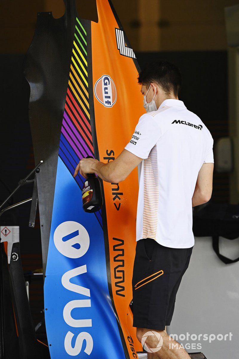 A McLaren team member cleans a pice if bodywork in the pit lane