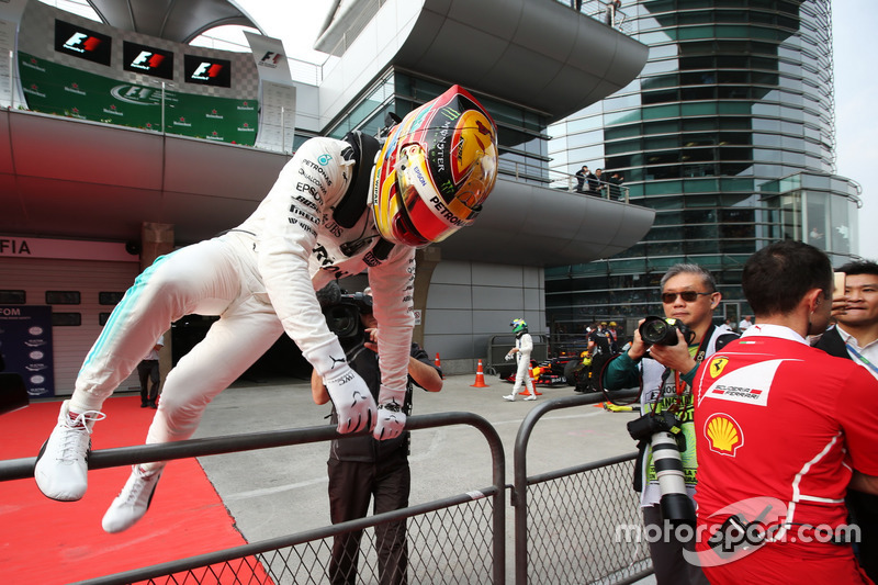 Lewis Hamilton, Mercedes AMG, scales a fence in parc ferme after taking pole position