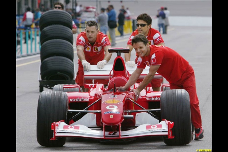 Ferrari mechanics push a car. United States GP, Indianapolis, United States. September 26th 2002.