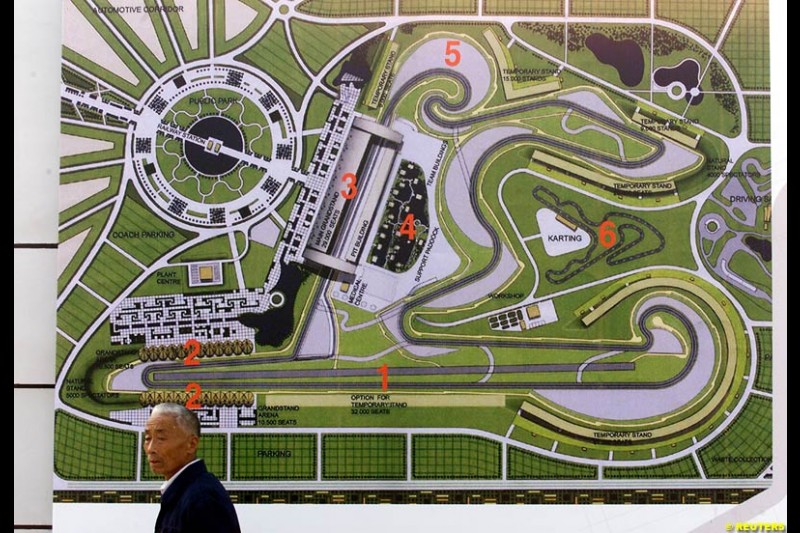 A Chinese resident walks past a floor plan of the Shanghai Circuit during its ground-breaking ceremony October 17, 2002. Shanghai has begun work on a 5.45-km (3.39-mile) racetrack north of the city, designed to look like the first Chinese character in the city's name and quot;shang and quot;.