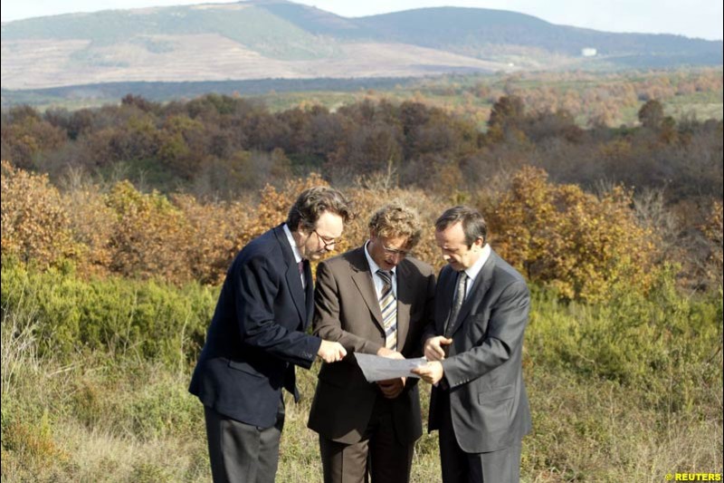 Formula One race track architect Hermann Tilke (center), flanked by Turkey's car and motor sports association chairman Mumtaz Tahincioglu (right) and an official from Turkish F1 committee Mehmet Karabeyoglu (left), looks at a map as he inspects a field on which a future track may be built for a Formula One Grand Prix in Istanbul November 26, 2002.