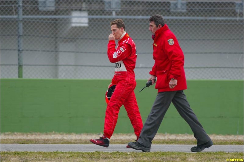 Michael Schumacher walks back to the pits after his Ferrari F2003-GA broke down during testing at the Imola circuit in Italy. 17th February, 2003.