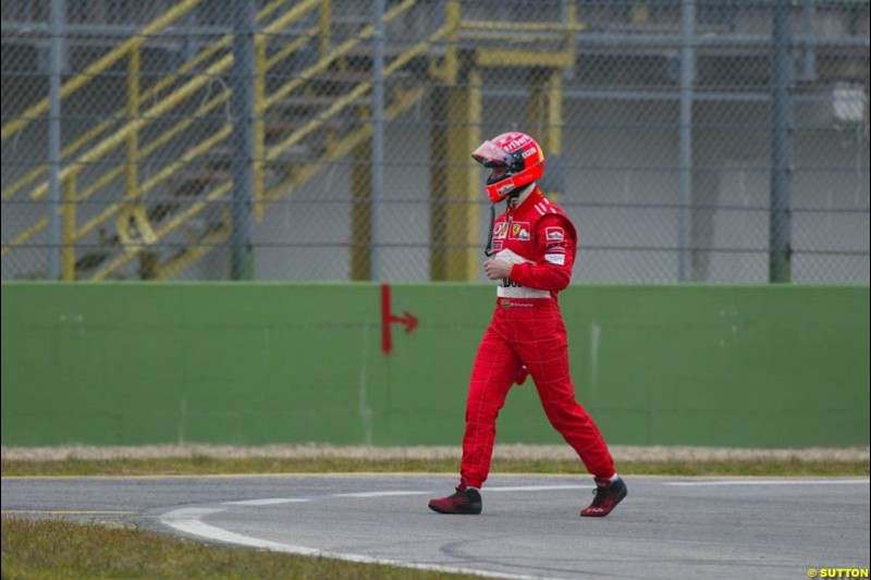 Michael Schumacher walks back to the pits after his Ferrari F2003-GA broke down during testing at the Imola circuit in Italy. 17th February, 2003.
